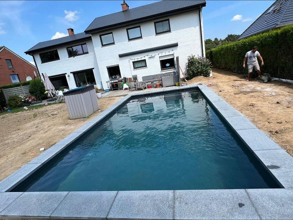 Piscine finie avec margelles, jardin en aménagement