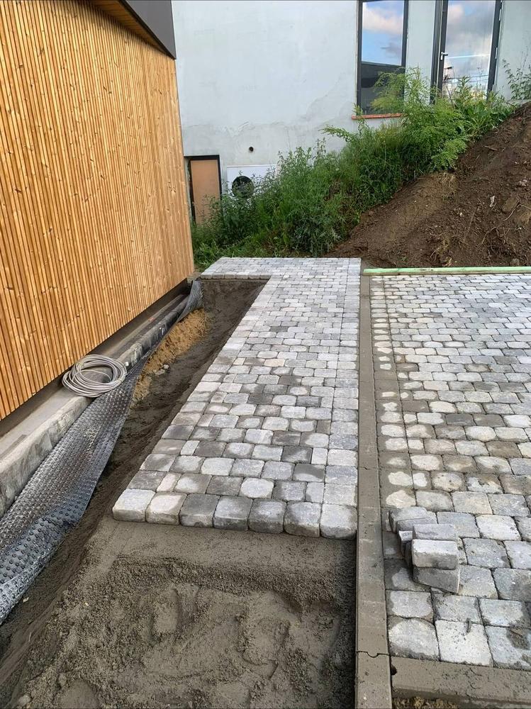Pose de pavés le long d'un bardage bois, base en sable