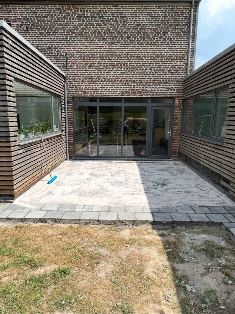 Terrasse en pierre naturelle fraîchement posée derrière une extension