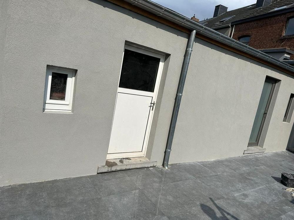 Extension enduite grise avec terrasse en pierre