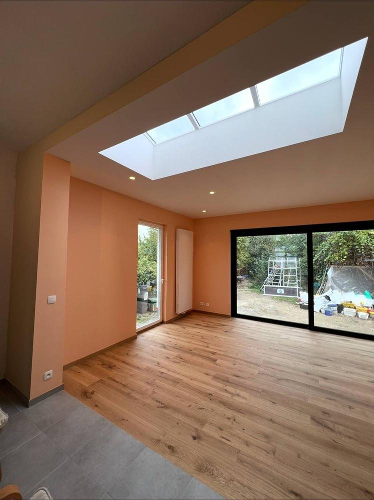 Extension avec puits de lumière, murs terracotta et parquet, baies vitrées sur jardin