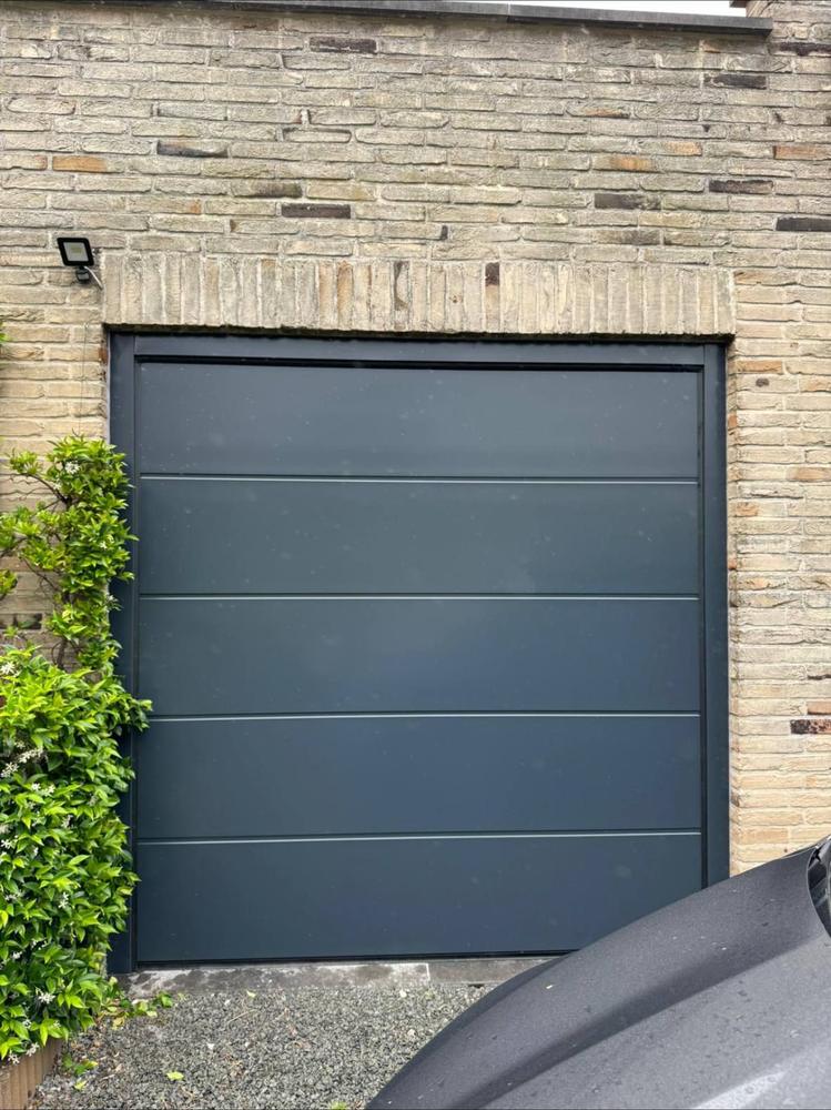 Porte de garage sectionnelle grise ouverte, façade blanche