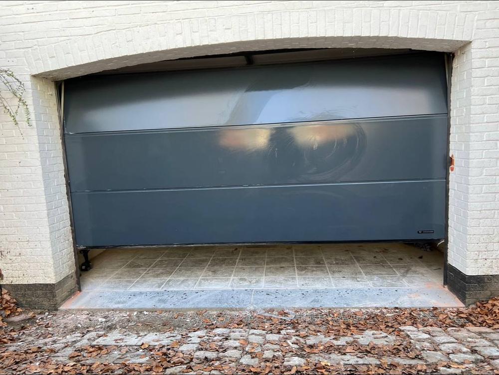 Porte de garage sectionnelle anthracite posée sur mur en pierre