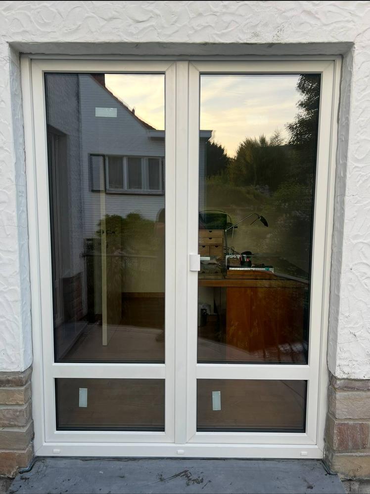 Porte-fenêtre PVC à double battant donnant sur le jardin